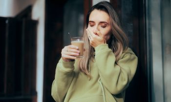 Femmes qui ressent de la sensibilité dentaire en buvant un café